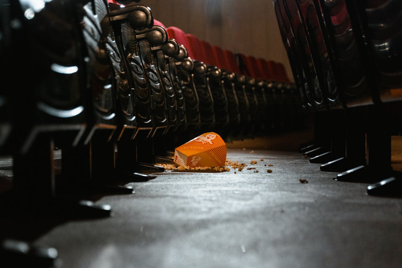 Empty movie theater aisle with spilled popcorn creating a messy scene.